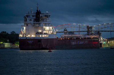 Illuminated commercial dock by sea against sky