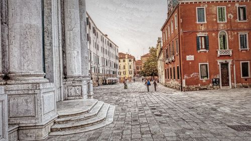 Footpath amidst buildings against sky