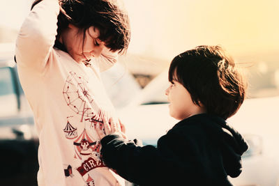 Side view of siblings standing outdoors