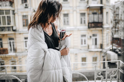 Full length of woman using mobile phone in city