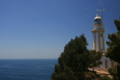 Lighthouse by sea against sky