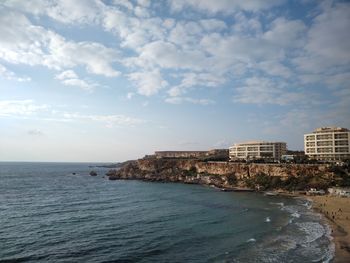 Scenic view of sea by buildings against sky