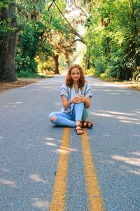 Portrait of young woman sitting on road