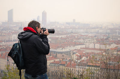 Rear view of man photographing cityscape