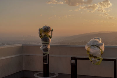 Binoculars on balcony against sky during sunset