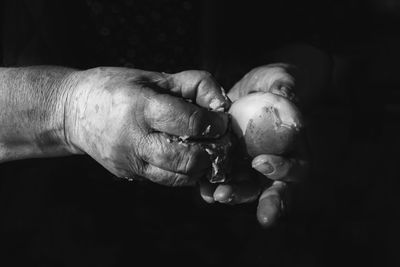 Cropped hands peeling prepared potato