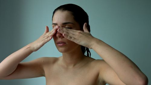 Portrait of shirtless young woman against gray background