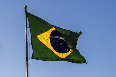 Low angle view of brazilian flag against clear blue sky