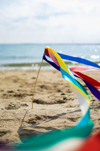 Scenic view of beach against sky with ribbons swaying in a wind.