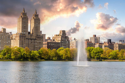 Buildings by river against sky