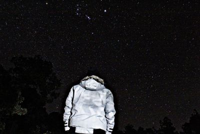 Rear view of man standing against star field at night