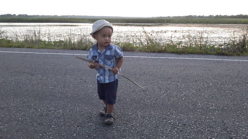 Full length of boy standing on road against sky