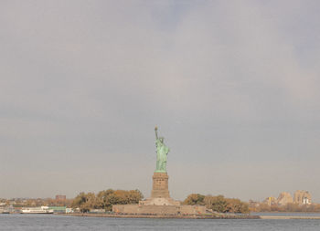 Liberty lady by sea against sky