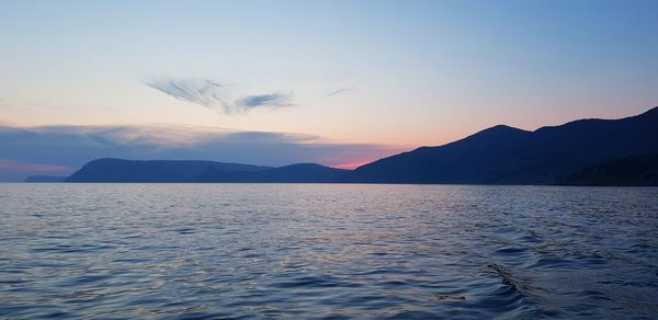 Scenic view of sea and mountains against sky during sunset