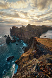 Rock formations on shore against sky during sunset