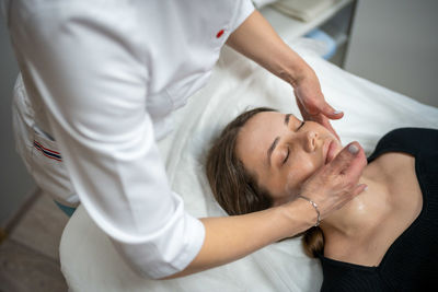 Beautician applying face mask to customer at spa