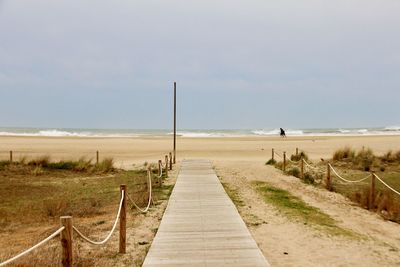 Footpath leading towards sea against sky