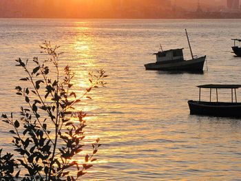 Boats in calm sea at sunset