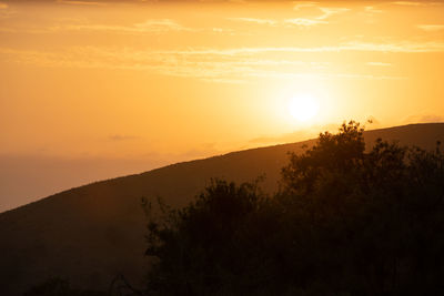 Scenic view of silhouette mountains against orange sky