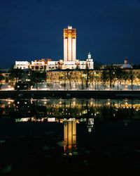 Reflection of illuminated lighthouse in city at night
