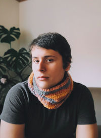 Portrait of young man against wall wearind a scarf 