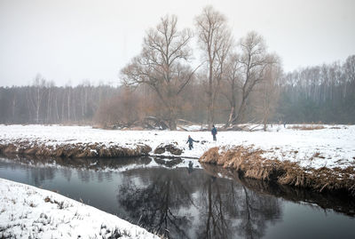 The small river flows lazily through a snowy misty winter landscape