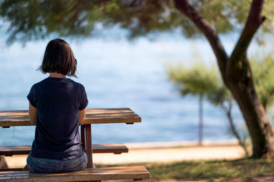 Rear view of woman sitting on picnic table