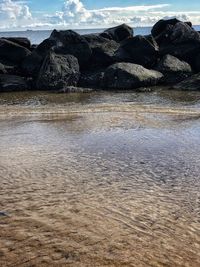 Rock formation on beach against sky