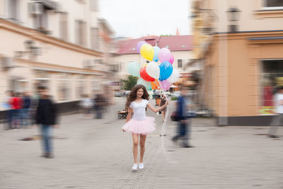 Full length of woman with umbrella on street in city