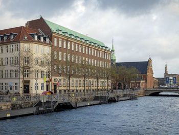 Buildings by river against sky