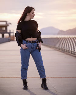 Young woman looking away while standing against sky