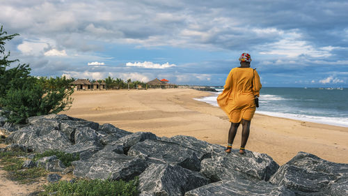 African woman standing on the edge of a beach in the tropical part of africa, keta ghana