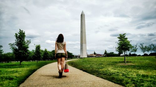 Rear view of woman with umbrella against sky