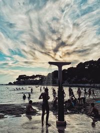 People enjoying at beach against sky