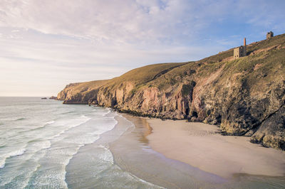 Scenic view of beach against cloudy sky