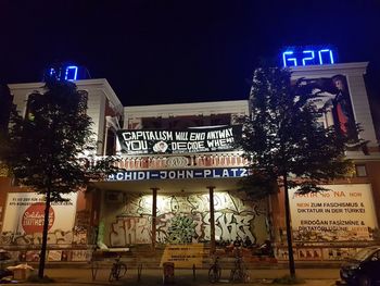 Low angle view of illuminated sign against building at night