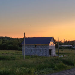 House on field against sky during sunset