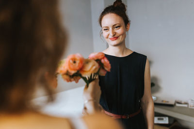 Smiling florist looking at customer with flowers