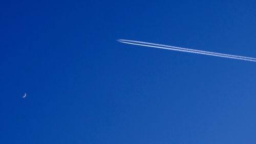 Low angle view of vapor trail against blue sky