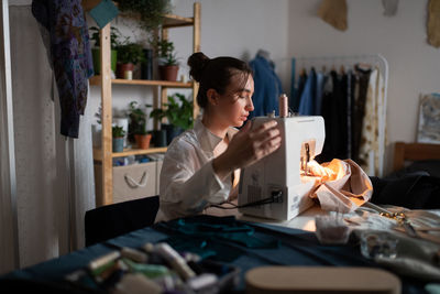 Female dressmaker using sewing machine at home