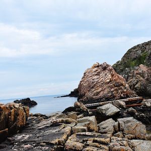 Rock formation by sea against sky