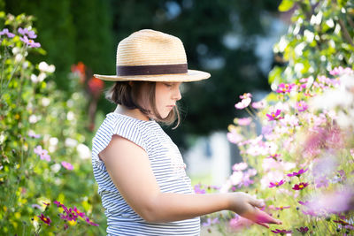 Midsection of woman wearing hat against pink flowering plants