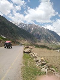 Car on mountain road against cloudy sky