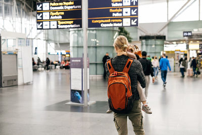 Family waiting near airport sign, arrival and departure area. man and happy girl ready to go by