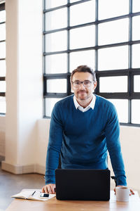 Portrait of young man using laptop on table