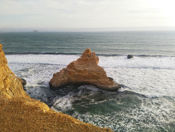 Rock formation in sea against sky