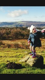 Portrait of girl standing on field against sky