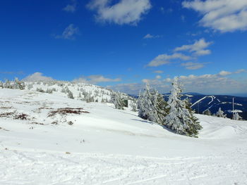 Snow covered landscape against blue sky