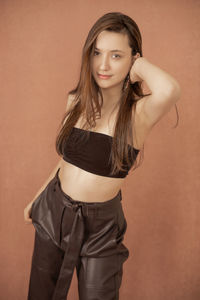 Portrait of a beautiful young woman standing against wall