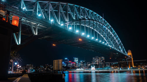 Illuminated harbour bridge over river at night